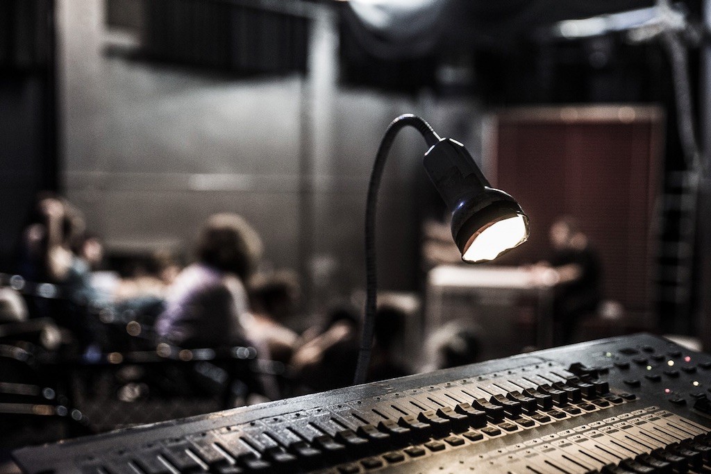 Μία κονσόλα ήχου και στο φόντο σπουδαστές θεάτρου